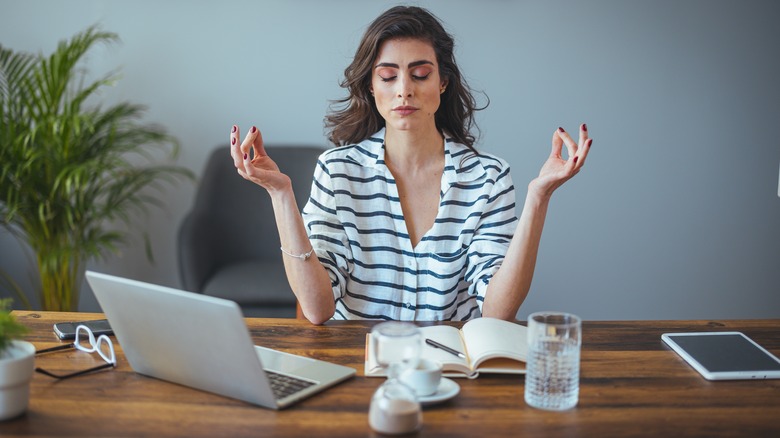 woman meditating at crowded desk