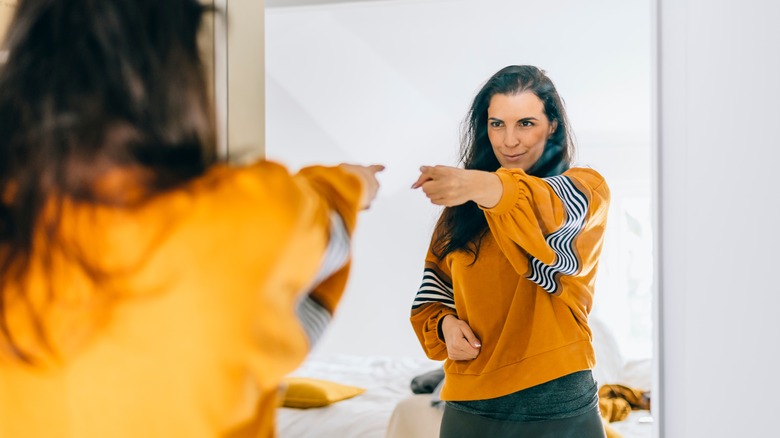woman pointing at reflection in mirror