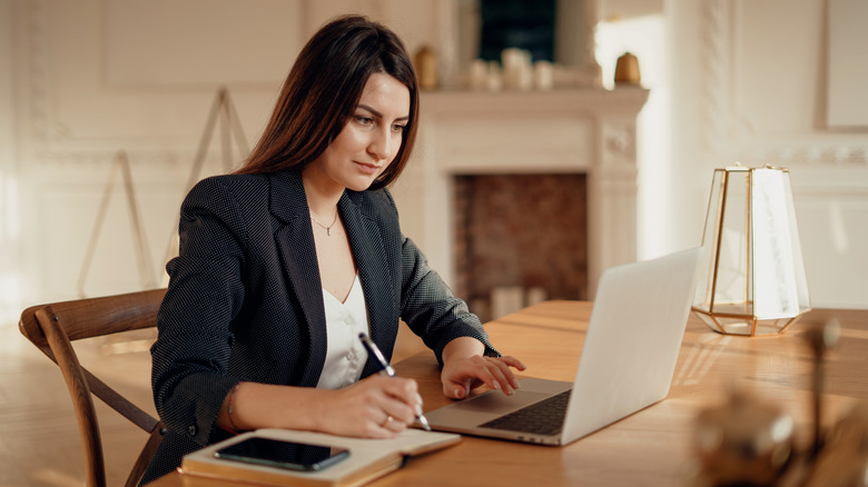 Woman takes notes at laptop