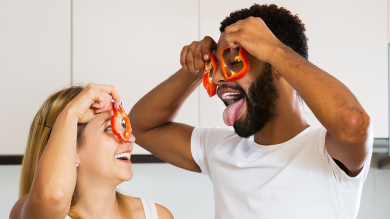 couple cooking with peppers to eyes 
