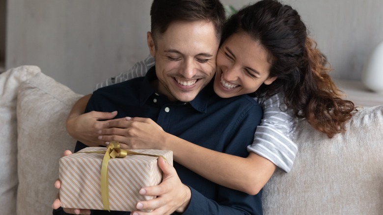 man holding gift woman hugging