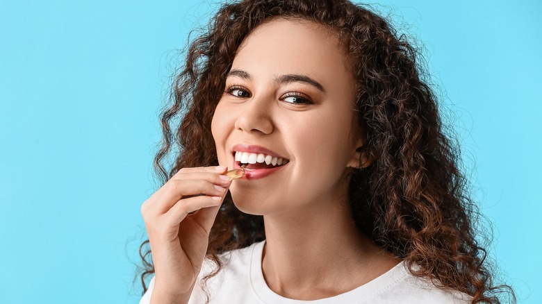 Model smiling taking fish oil capsule