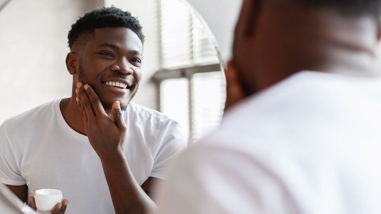 Model looking at skin in mirror