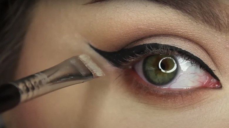 girl applying concealer on eyeliner