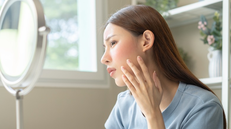 Woman looking at spot on skin in sunshine