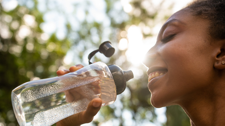 Woman drinking water outdoors in the summer