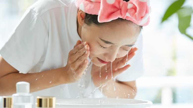 Woman washing face near plant and sunshine