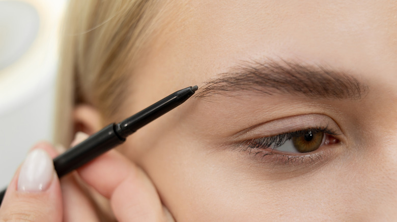 Woman drawing in eyebrows