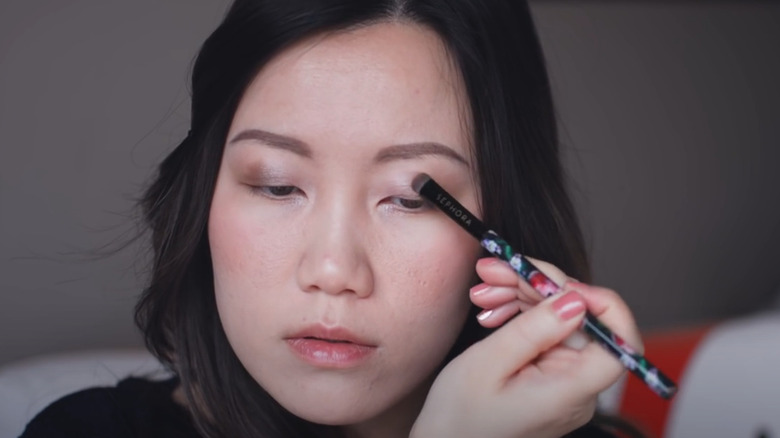 Asian woman applying eyeshadow