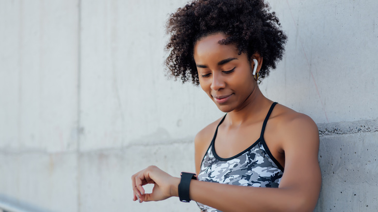 Woman in activewear checks fitness tracker during workout