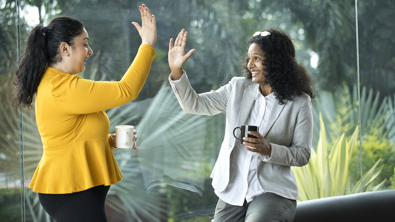 two people high-fiving with coffee