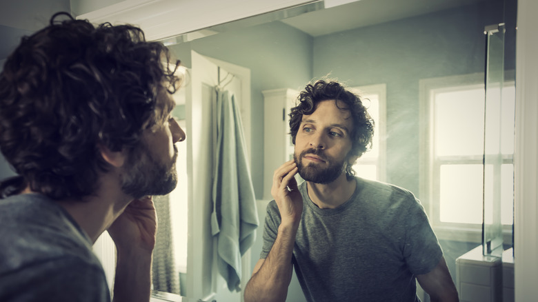 Person observing their beard in mirror