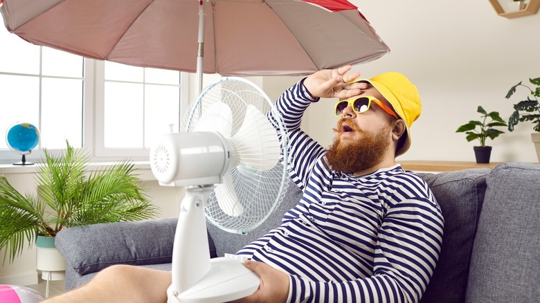 Person sitting on couch near fan