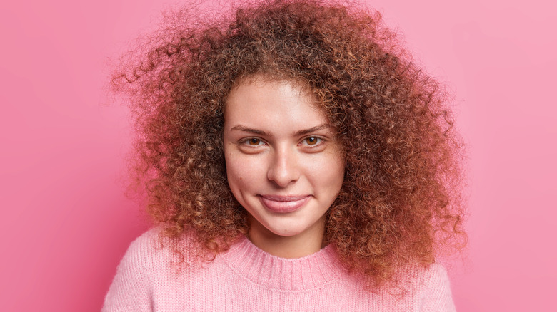 Curly-haired woman pink background