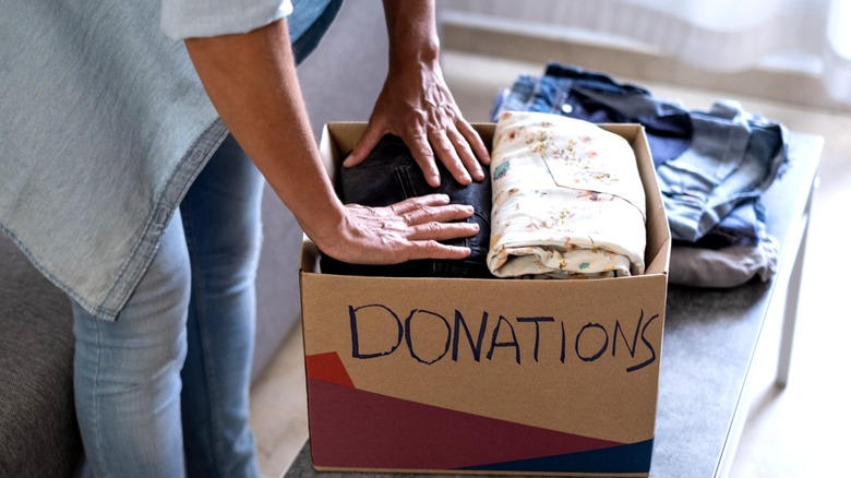 A woman placing folded clothes into a donations box.