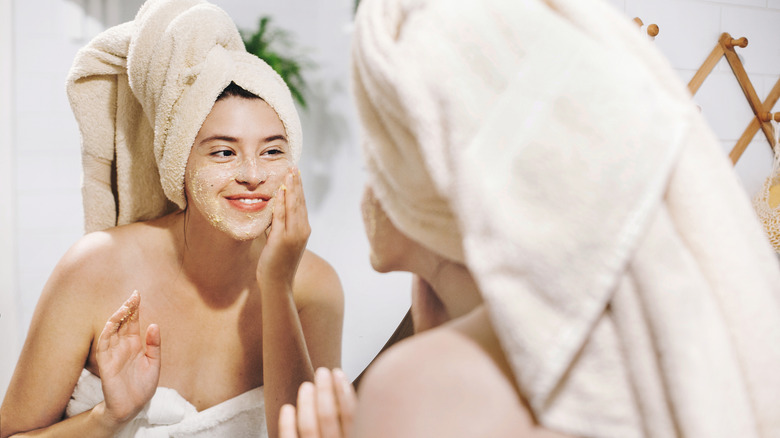 Woman applying scrub on her face