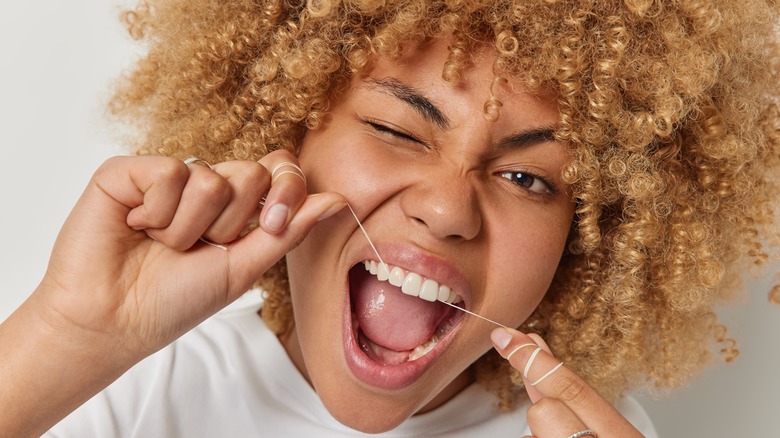 A woman flossing her teeth