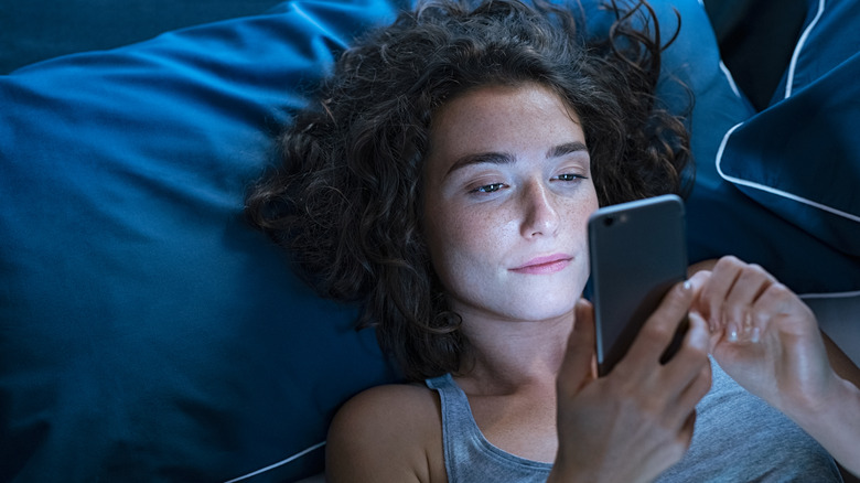 woman using phone in bed