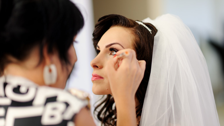 woman putting makeup on bride