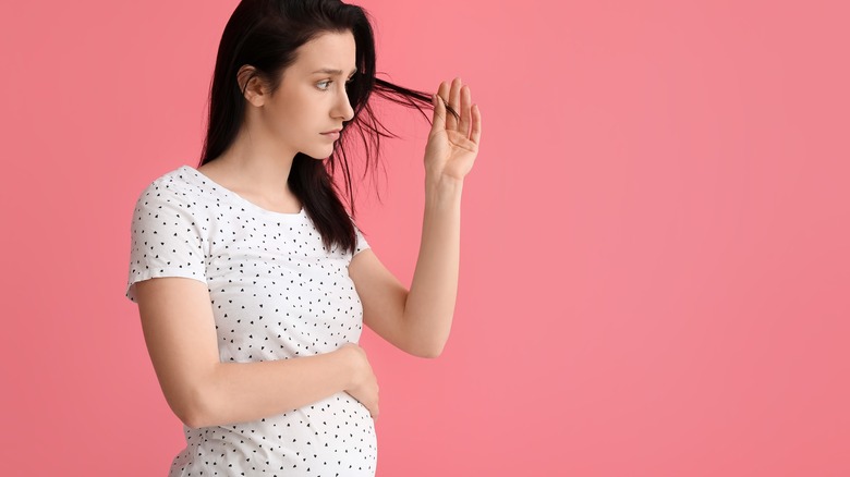 A pregnant woman looking at her hair 