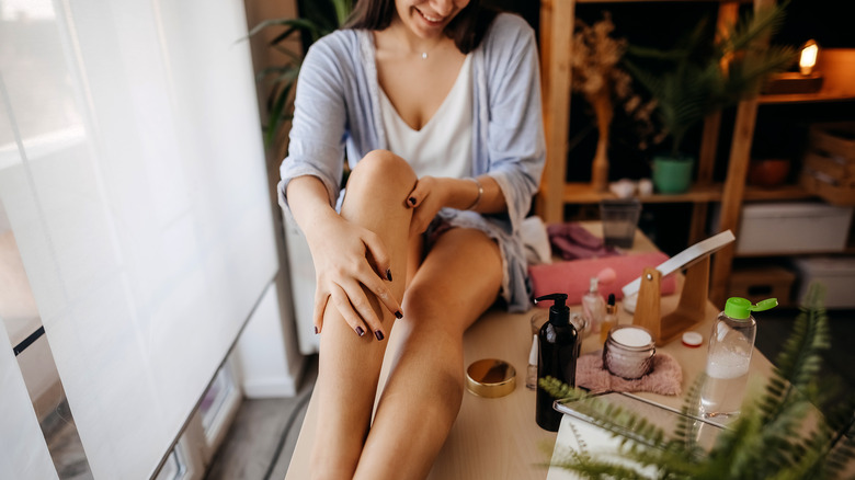 Woman applying moisturizer to legs