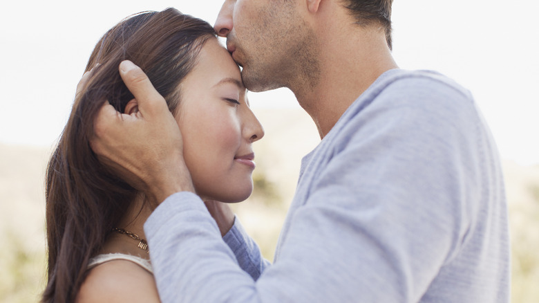 Man kissing partner on forehead