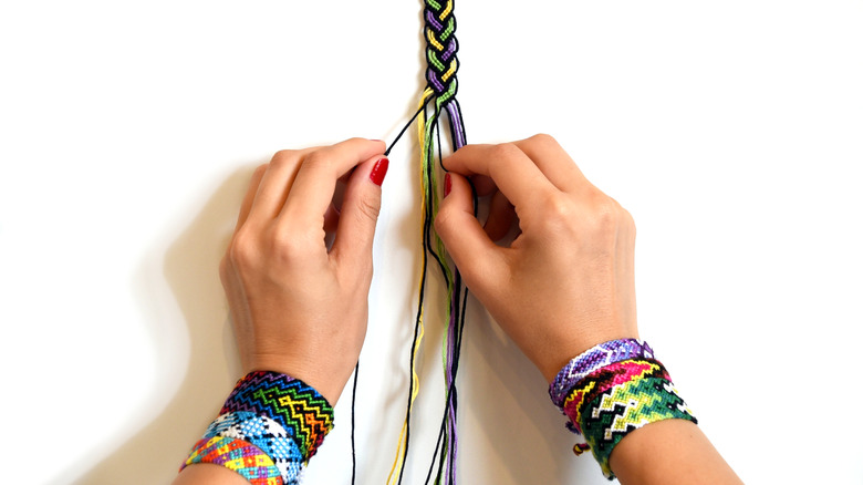 Hands weaving a friendship bracelet