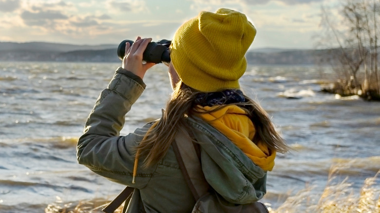 Woman using binoculars at lake