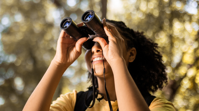 Woman using binoculars in woods