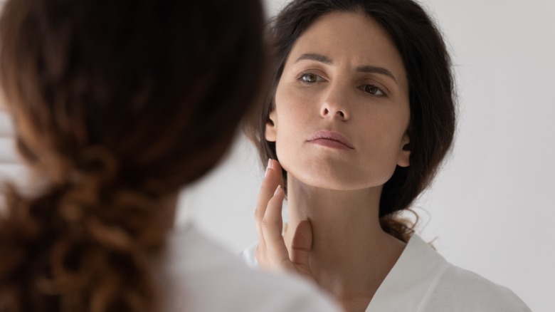 Woman examining wrinkles in mirror