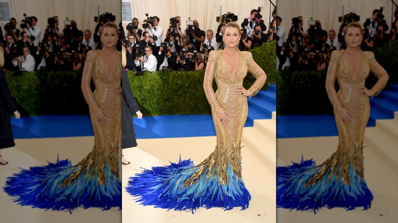 Blake Lively posing on the Met Gala steps in a gold and blue dress