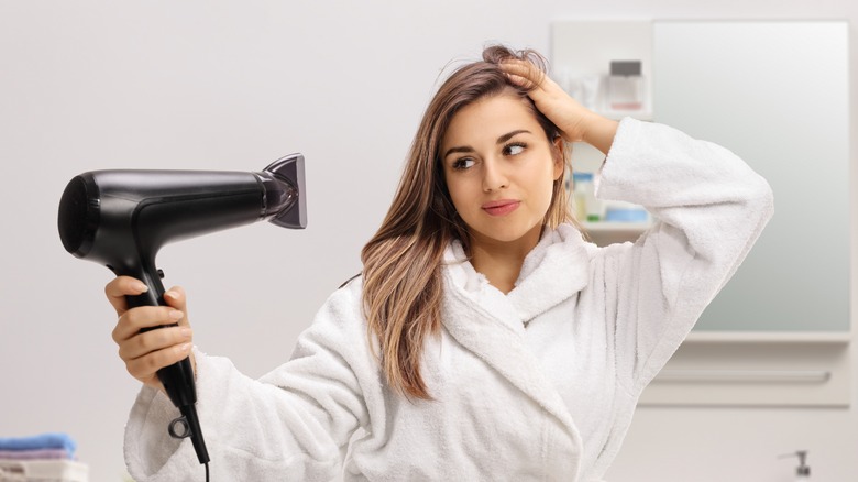 Woman blowdrying hair bathrobe