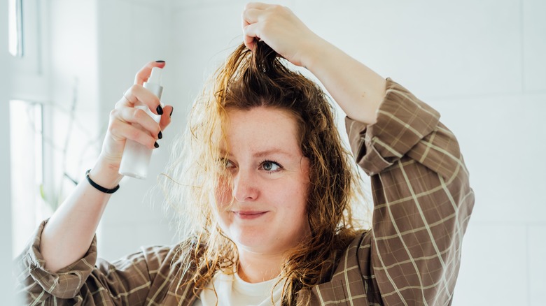 Woman spraying serum on damp hair