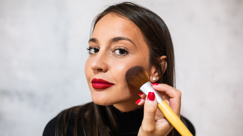 woman applying blush with brush