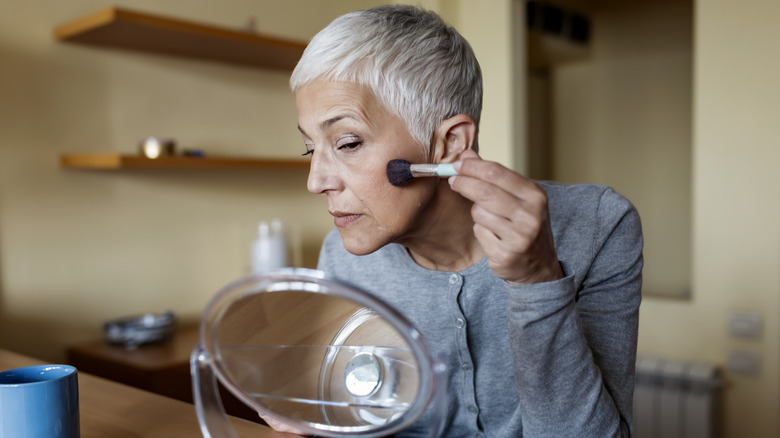 Woman gray hair applying blush