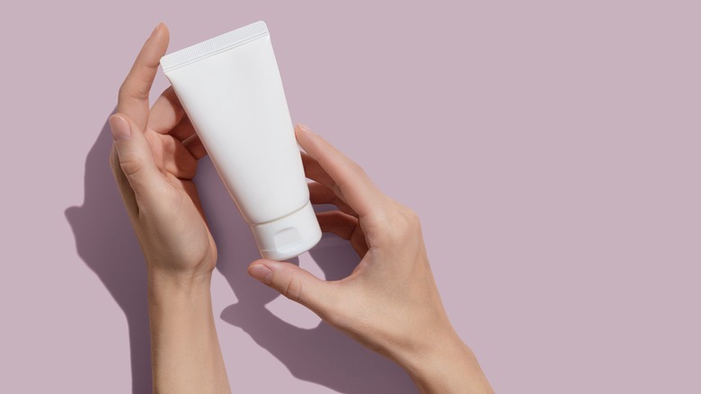 hands holding white cosmetic tube