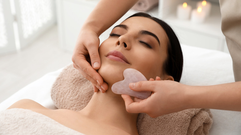 Woman receiving facial acupuncture with Gua Sha tool