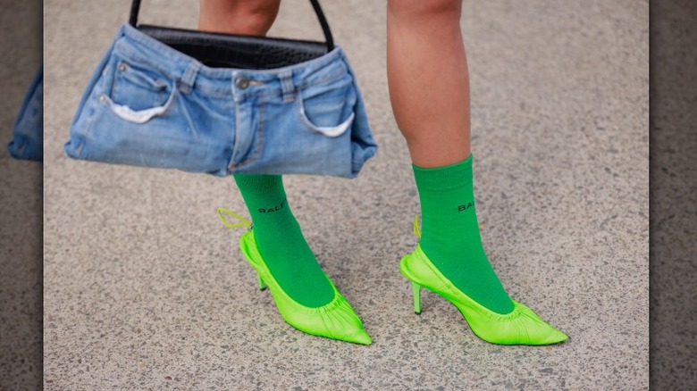 Woman in green socks and shoes with denim handbag