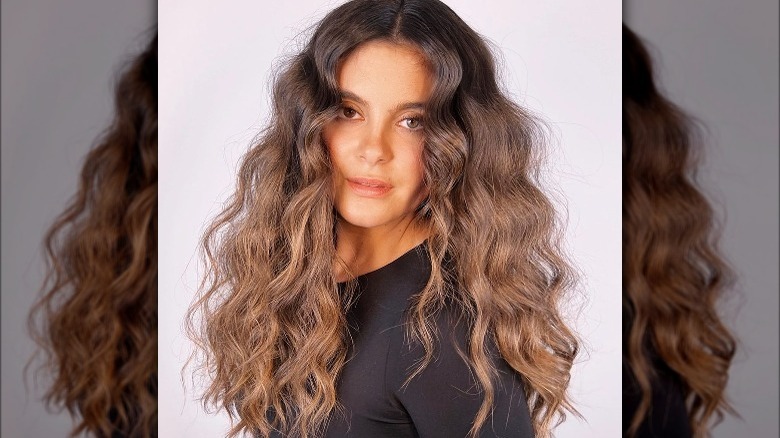Woman with long wavy hair and a middle part