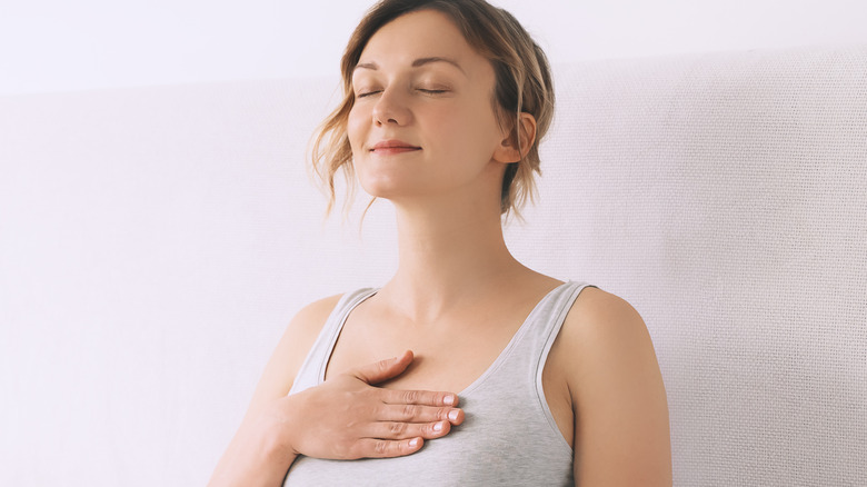 Smiling woman breathing with hand on chest