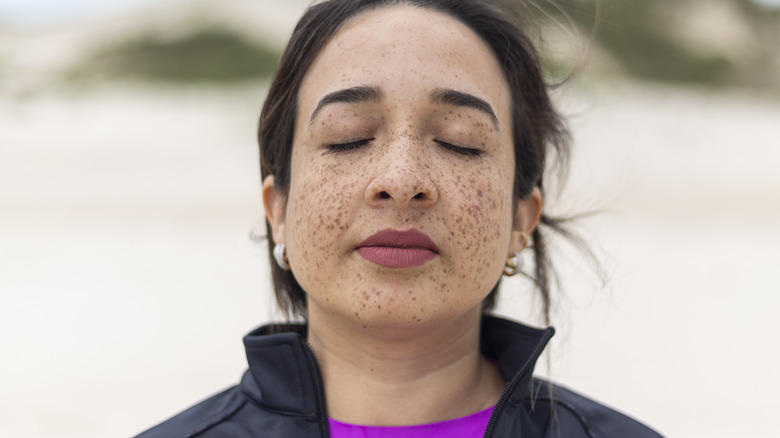 Freckled woman breathing on beach