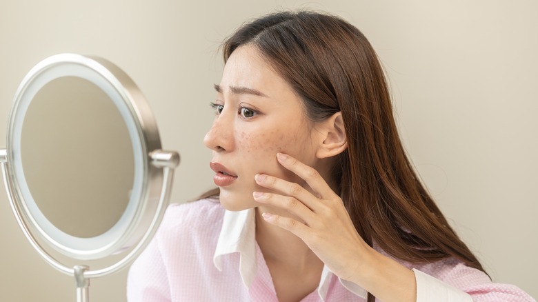 Woman checking acne in mirror
