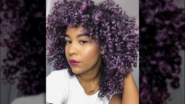 A woman with curly eggplant-colored hair