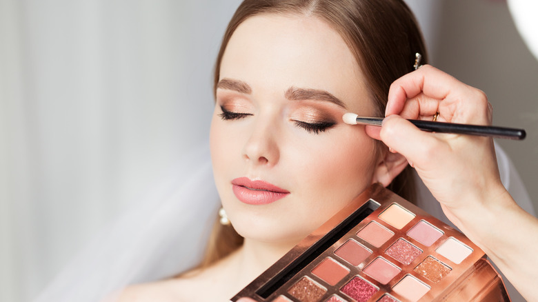 Applying eyeshadow to bride