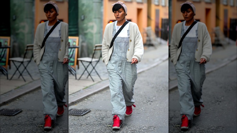 Woman wearing overalls and red sneakers