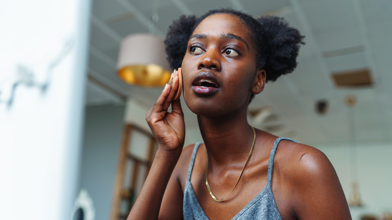 Woman applying skincare in mirror