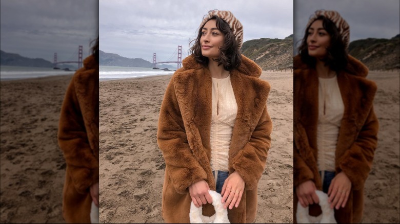 Woman wears brown fur coat and cream blouse 