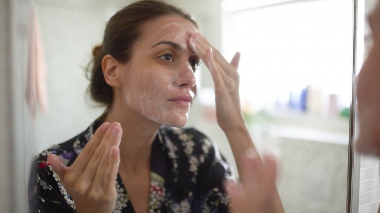 Woman washing face in mirror
