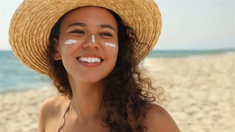 Woman in sunhat with sunscreen on face