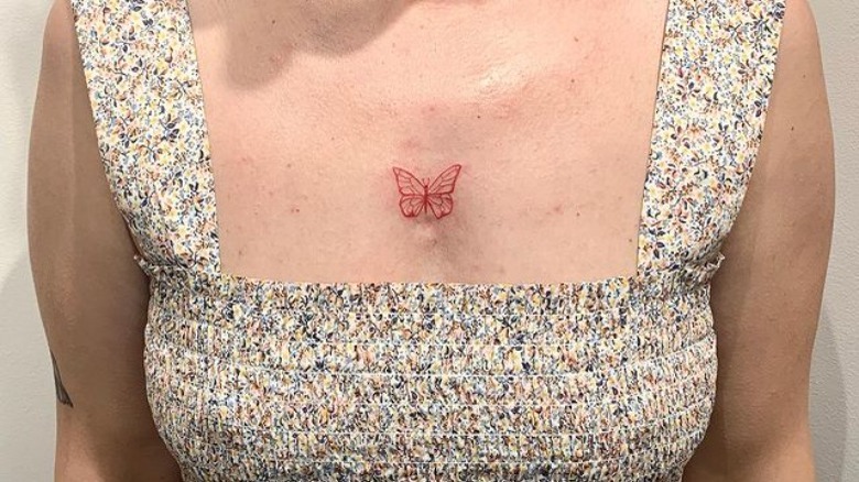 Butterfly tattooed in red ink on chest